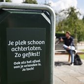 Afvalbak met tekst: Je plek schoon achterlaten. Zo gefikst! Ook als het afval van je vrienden is. Ja toch!