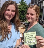 Twee studenten houden een flyer omhoog met de tekst neem gerust je eigen verpakking mee