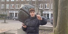 Still uit video 1 van het Peukenproject: een jongen staat voor een beeld van een vis, met een peuk in zijn hand.