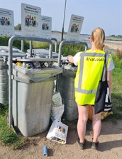 Een afvalcoat checkt volle vuilnisbakken bij het Waalstrand.