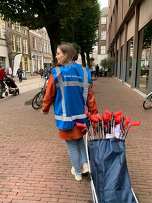 Een afvalcoach loopt op straat met afvalgrijpers, bedoeld om uit te delen onder ondernemers in Arnhem.