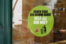 Een ruit met daarop een raamsticker met de tekst: Samen voor een schone buurt, help jij ook mee?
