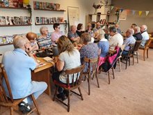 Bijeenkomst Tilburg Schoon, groep vrijwiligers overlegt aan een lange tafel.